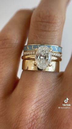 a woman's hand with two wedding rings on top of her finger and the ring has an oval diamond in it