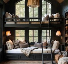 a bunk bed with lots of pillows and blankets on it in front of a window