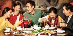 a group of people sitting around a table with food and drinks in front of them