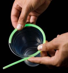 two hands are holding plastic cups with straws in them and one hand is pointing to the cup