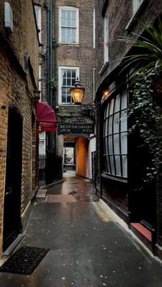 an alley way with brick buildings and a red umbrella on the sidewalk next to it