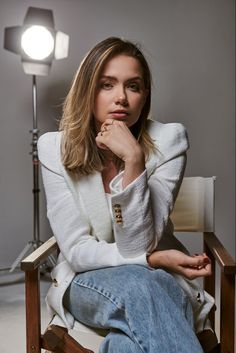 a woman sitting in a chair with her hand on her chin and looking at the camera