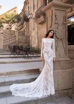 a woman in a white wedding dress standing on some steps with her arms behind her back