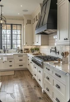 a large kitchen with white cabinets and wood flooring is seen in this image from the inside