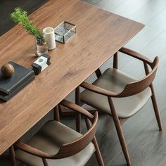 a wooden table with chairs around it and a book on the end shelf next to it