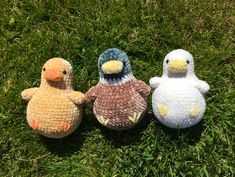 three small stuffed birds sitting on top of green grass