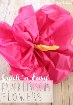 a pink paper flower sitting on top of a wooden table