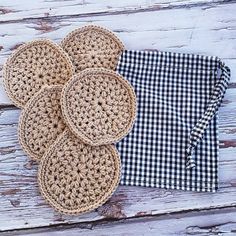 four crocheted placemats on top of a wooden table next to a black and white checkered napkin