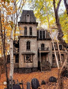 an old wooden house in the woods surrounded by trees and fallen leaves with pumpkins on the ground