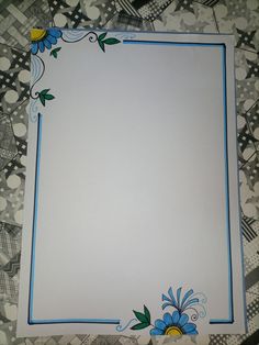 a white paper with blue trim and flowers on the edges is laying on a patterned tablecloth