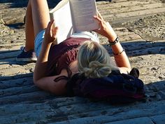 a woman laying on the ground reading a book