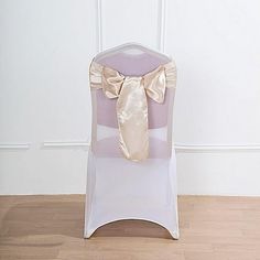 a white chair with a gold bow on it's back and the seat cover is empty