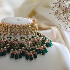 an elaborate necklace is displayed on a mannequin with flowers in the foreground