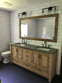 a bathroom with two sinks, a toilet and a large mirror above the sink in it