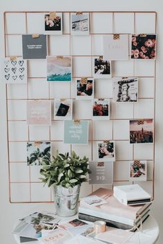 a white table topped with lots of pictures and plants next to a wall mounted memo board