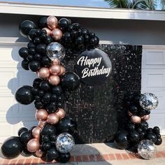 a happy birthday sign made out of black and rose gold balloons in front of a garage