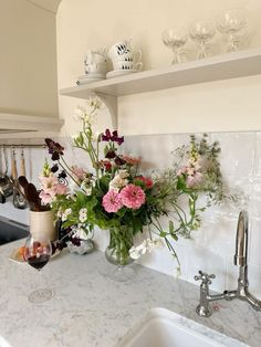 a vase filled with lots of flowers sitting on top of a kitchen counter next to a sink