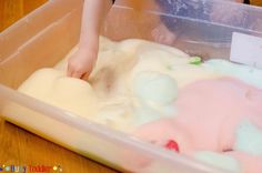 a child is playing with colored play dough in a plastic container on the table,