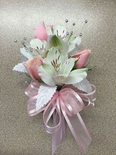 a bouquet of flowers with pink ribbons and pearls