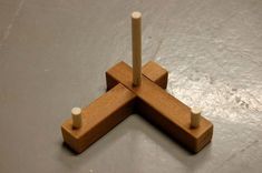 four wooden pegs are arranged in the shape of an x on a gray surface