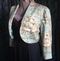 This aqua toile Jacket features a sweet romantic couple in a garden setting.  Fully lined lightweight jacket with long tapered sleeves, this retro bolero sports a shawl collar. Jacket is cotton, lining is polyester. Size 10 fits about a 34" bust. Fitted Blazer For Spring Daywear, Green Fitted Outerwear For Daywear, Fitted Spring Blazer For Daywear, Vintage Fitted Outerwear For Daywear, Fitted Vintage Outerwear For Daywear, Vintage Spring Daywear Outerwear, Spring Vintage Outerwear With Vintage Print, Vintage Spring Outerwear For Daywear, Vintage Outerwear For Spring Daywear