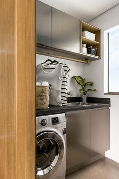 a washer and dryer in a small room next to a window with open shelving