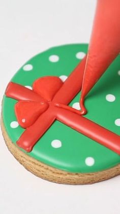 a cookie decorated like a cross on top of a green polka dot covered plate with red icing