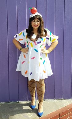 a woman standing in front of a purple wall wearing an ice cream dress and hat