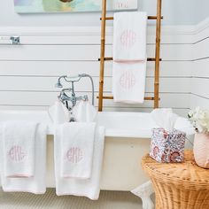 three personalized towels hanging on a towel rack next to a bathtub and sink