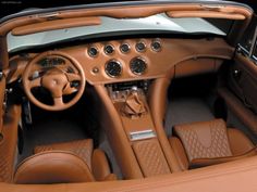 the interior of a car with brown leather seats and dashboards, including an automatic steering wheel