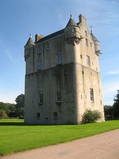 an old castle like building sitting on top of a lush green field