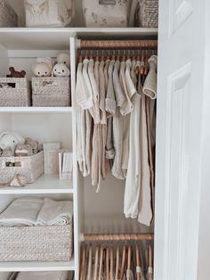 an organized closet with clothes, baskets and other items in it's white shelves