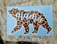 a sticker with the word mama written in leopard print on it sitting on top of a rock