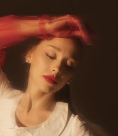 a woman with her eyes closed wearing a white shirt and red scarf over her head