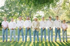 a group of men standing next to each other on top of grass covered ground in front of trees