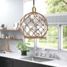 a kitchen area with a sink, window and light fixture in the middle of it