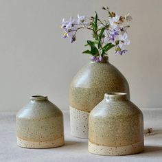 two vases with flowers in them sitting on a table