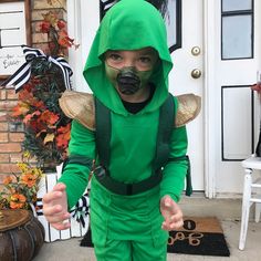 a little boy dressed up in a green costume