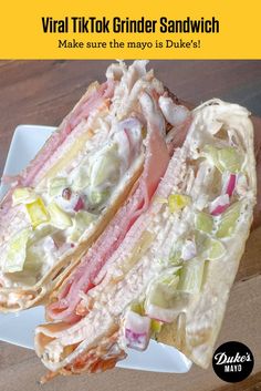 a sandwich cut in half sitting on top of a white plate next to a wooden table