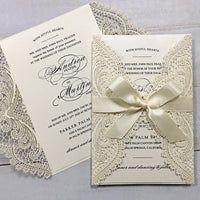 the wedding stationery is decorated with lace and satin ribbon as well as a bow