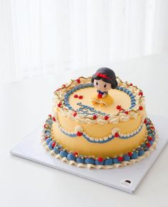 there is a yellow cake with blue and red decorations on the top, sitting on a white surface