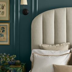 a bed with blue walls and white pillows in a room that is painted teal