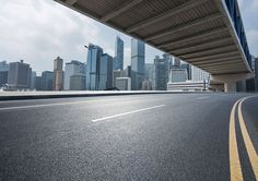 an empty highway with the city in the backgroung and skyscrapers behind it