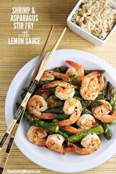 shrimp and asparagus stir fry with lemon sauce on a white plate next to chopsticks