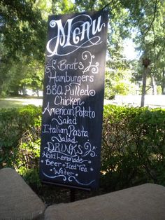 a menu sign in front of some bushes and trees with the word menu written on it