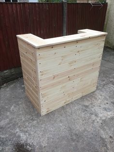 a large wooden box sitting on top of a cement floor next to a fenced in area