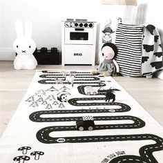 a child's room with black and white rugs on the floor, stuffed animals and toys