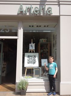 a young boy standing in front of an art store