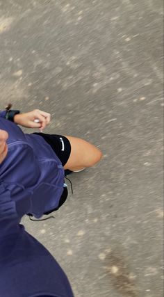 a woman in blue shirt and black shorts holding a white frisbee on street