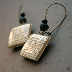 a pair of earrings made out of old book pages with beads hanging from the ends